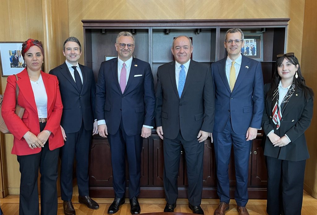 ALG 1 | MCG24 | موقع إلكتروني مغربي شامل متجدد على مدار الساعة Six professionally dressed individuals standing side by side in a wood-paneled office, smiling at the camera.