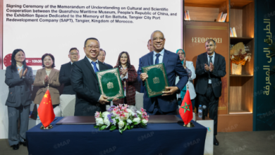 Officials sign a Memorandum of Understanding on cultural and scientific cooperation, standing behind a table with green documents and flags on display.