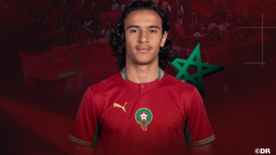 Ayoub-Bouaddi | MCG24 | موقع إلكتروني مغربي شامل متجدد على مدار الساعة Portrait of a footballer wearing a red Morocco national team jersey with the crest, facing the camera.