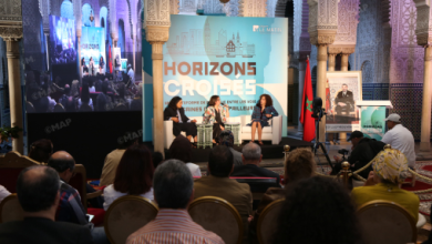 Panel discussion at the Horizons Croisés conference in an ornate room; three speakers sit on stage under a banner reading Horizons Croisés, with an audience and a camera recording.