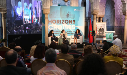 Panel discussion at the Horizons Croisés conference in an ornate room; three speakers sit on stage under a banner reading Horizons Croisés, with an audience and a camera recording.