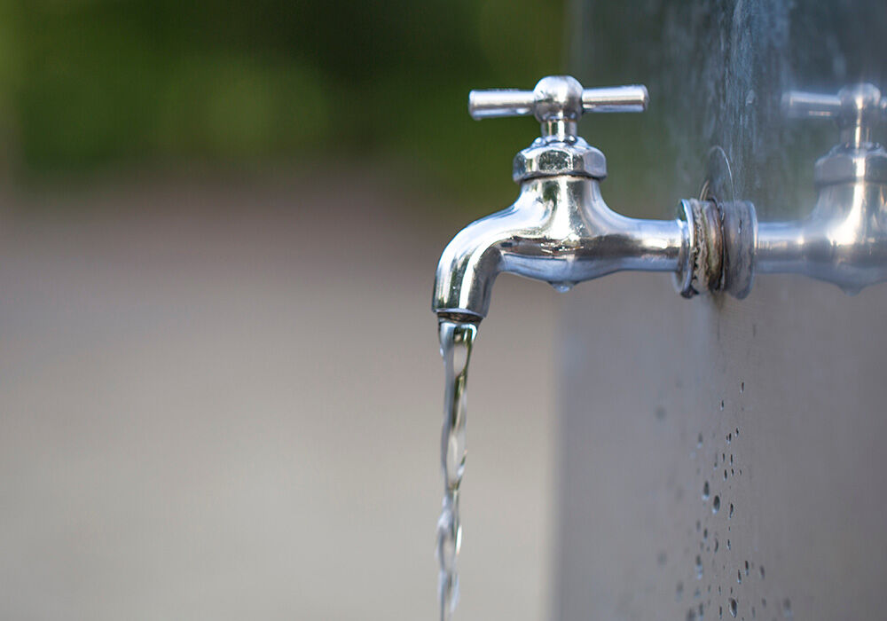 Chrome outdoor faucet with water streaming from the spout