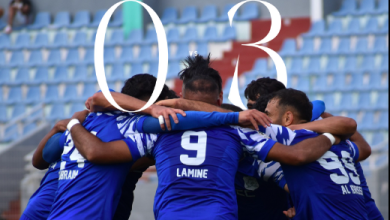Soccer players in blue jerseys form a tight huddle on the field, backs visible with number 9 Lamine.