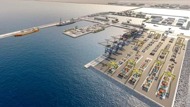 Aerial view of a busy container port with cranes, docks, and rows of stacked shipping containers by the water