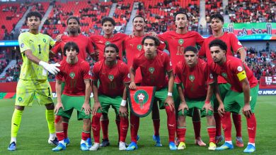 Moroccan national football team posing for a group photo on the field, goalkeeper in yellow on the left.