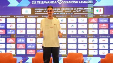 Diamond-League_webp | MCG24 | موقع إلكتروني مغربي شامل متجدد على مدار الساعة Male athlete standing on a podium in front of a sponsor-heavy backdrop with Diamond League banners, giving a thumbs-up.