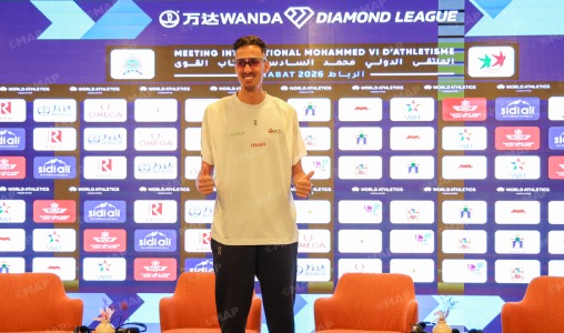 Diamond-League_webp | MCG24 | موقع إلكتروني مغربي شامل متجدد على مدار الساعة Male athlete standing on a podium in front of a sponsor-heavy backdrop with Diamond League banners, giving a thumbs-up.