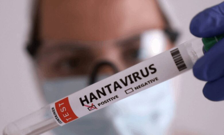 Scientist wearing goggles and a mask holds a test tube labeled HANTAVIRUS with positive/negative checkboxes visible in the foreground.