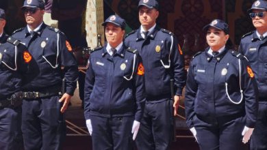 Group of uniformed officers standing in a line at a formal event, wearing navy blue attire and caps with badges.