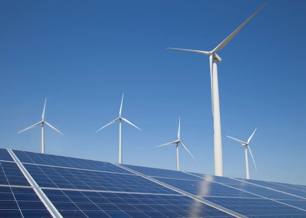GettyImages-521957160 | MCG24 | موقع إلكتروني مغربي شامل متجدد على مدار الساعة Wind turbines rise above solar panels under a clear blue sky, showcasing renewable energy infrastructure.