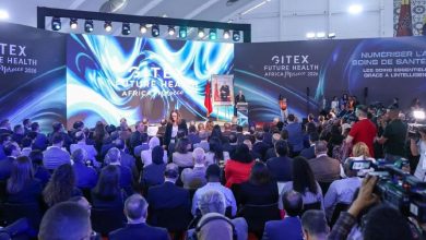 Stage at a large conference with blue, swirling backdrop reading 'GITEX Future Health Africa Morocco 2026' and a seated audience in front of a presenter podium.