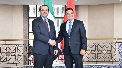 HISGFWLXcAAOsnJ | MCG24 | موقع إلكتروني مغربي شامل متجدد على مدار الساعة Two men in dark suits shake hands in a formal setting with flags behind them.