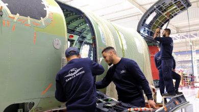 HIcTmhsWIAA6C2i | MCG24 | موقع إلكتروني مغربي شامل متجدد على مدار الساعة Engineering team in navy uniforms assembling a large green aircraft fuselage inside a bright hangar.