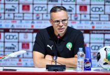 IMG-20260317-WA0024-1024x568 | MCG24 | موقع إلكتروني مغربي شامل متجدد على مدار الساعة Male football official with Morocco crest speaks at a press conference, microphone in front, plus a water bottle, Pepsi can, model airplane, and a football on the table.