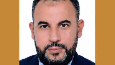 IMG-20260522-WA0006 | MCG24 | موقع إلكتروني مغربي شامل متجدد على مدار الساعة Professional headshot of a bearded man in a navy suit and red tie, with a white background and cropped framing.