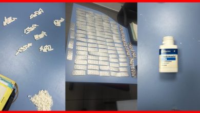 Blue table covered with many white tablets in blister packs arranged in rows; scattered pills and a pile of crushed white powder on the left, and a white bottle labeled Trankimazín 2 mg on the right.
