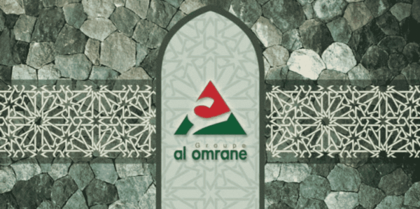 Arched panel on a stone wall displaying the 'al omrane' group logo in red and green. The panel features geometric patterns and is flanked by decorative stone walls.