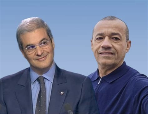 Two men pose together against a blue gradient background; one in a suit and tie, the other in a dark polo.