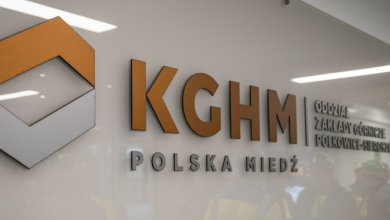 Corporate sign on a white wall with orange KGHM letters and the Polish Copper emblem.