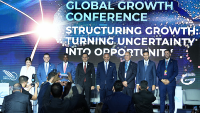 Dignitaries on stage at a Global Growth Conference; photographers in the foreground, backdrop displays the conference slogan.