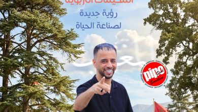 قائد يبتسم وهو يشير إحالة نحو الكاميرا أمام مخيم صيفي مع أطفال وشبان حوله وتُّخيمات في الخلف.