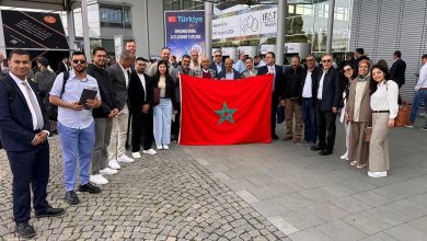 Group of professionals posing with a red Moroccan flag at an expo entrance, with banners in the background saying Türkiye and Engineering a Cleaner Future.