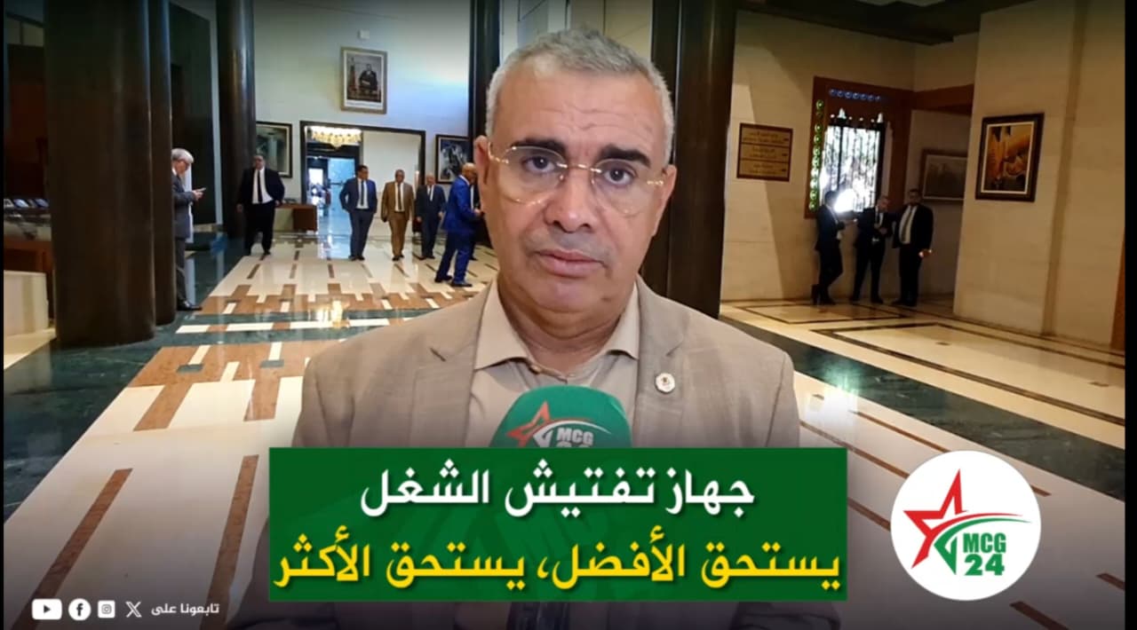 WhatsApp Image 2026-05-13 at 095419 | MCG24 | موقع إلكتروني مغربي شامل متجدد على مدار الساعة Man in a beige suit being interviewed in a marble lobby, with a green caption banner in Arabic and the MCG24 logo visible on the right.