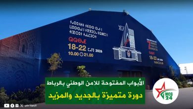 Blue exterior of a venue with Arabic promotional banners for the National Security Open House in Rabat, May 18–22, 2026; a green caption overlay and a circular MCG24 logo in the corner.