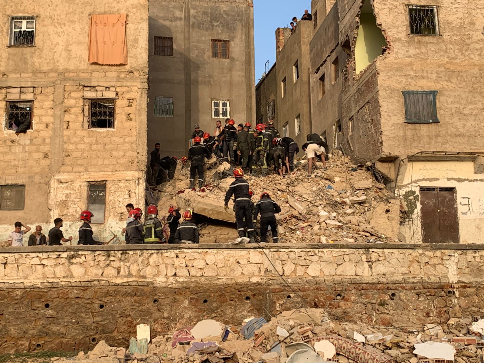 WhatsApp Image 2026-05-21 at 124842 | MCG24 | موقع إلكتروني مغربي شامل متجدد على مدار الساعة Rescue workers in red helmets search debris from a collapsed building amid urban rubble.