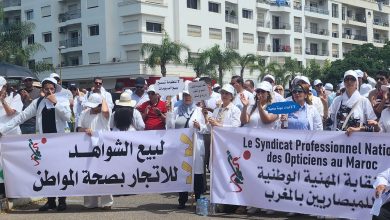WhatsApp Image 2026-05-25 at 112804 | MCG24 | موقع إلكتروني مغربي شامل متجدد على مدار الساعة Group of protesters in white clothing holding large banners with Arabic and French text, in front of a white apartment building.
