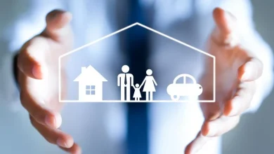 Hands surround a white outline of a house, family, and car inside a protective shape, symbolizing home insurance protection for a family.