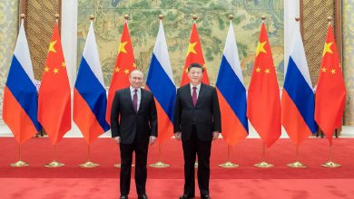 Two world leaders, Vladimir Putin and Xi Jinping, stand side by side on a red carpet with Russian and Chinese flags behind them.