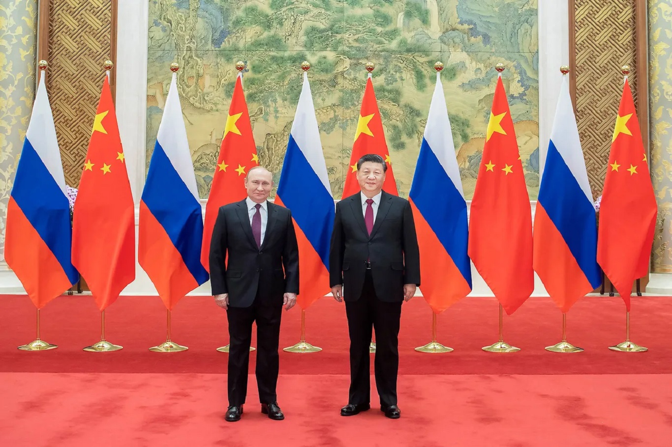 Two world leaders, Vladimir Putin and Xi Jinping, stand side by side on a red carpet with Russian and Chinese flags behind them.