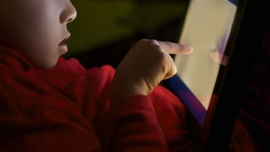 child find bad content on the Internet | MCG24 | موقع إلكتروني مغربي شامل متجدد على مدار الساعة Child in a red shirt touching a glowing tablet screen in low light, profile visible
