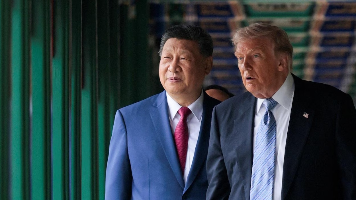 Two men in suits walk together down a green-painted corridor, looking ahead with serious expressions.