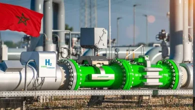 Morocco flag beside a large green hydrogen pipeline equipment in an industrial plant.