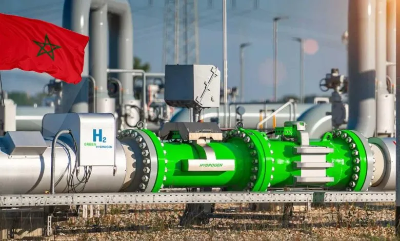 Morocco flag beside a large green hydrogen pipeline equipment in an industrial plant.