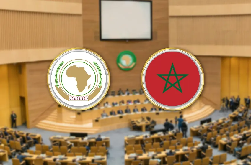 Formal international meeting in a chamber; two large round emblems above delegates: Africa Union on the left and Morocco flag on the right.