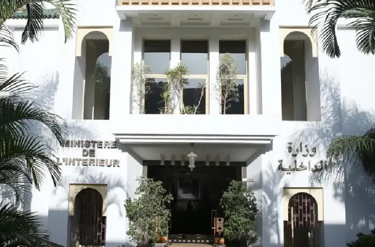 White government building with signs in French and Arabic reading 'Ministère de l'Intérieur', palm trees flanking a central entrance under a canopy.