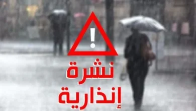 indaria_1658575527_1697892324-1 | MCG24 | موقع إلكتروني مغربي شامل متجدد على مدار الساعة Red warning triangle with exclamation mark and Arabic text 'نشرة إنذارية' over a rain scene with people under umbrellas.