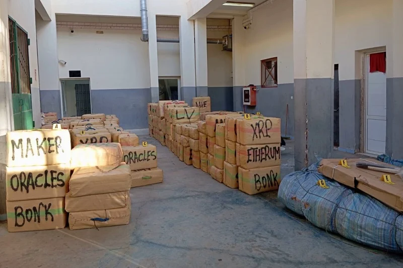 Indoor storage area with stacked brown boxes labeled with cryptocurrency names (XRP, Ethereum, Bitcoin, Maker, Oracle).