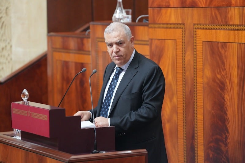 laftit-parlement | MCG24 | موقع إلكتروني مغربي شامل متجدد على مدار الساعة Man in a dark suit delivering a speech at a wooden podium with two microphones in a wood-paneled chamber.