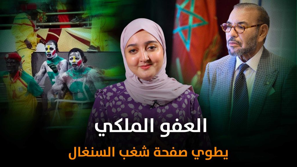 العفو الملكي عن المشجعين السنغاليين: رسالة من الدولة تتجاوز منطق العقاب لتفتح آفاق الأخوة Hero banner with a smiling woman in a lavender hijab center, a man in a suit to her right, and colorful background performers; Arabic headline overlays