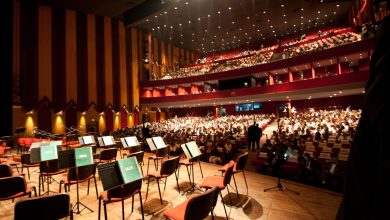 ml | MCG24 | موقع إلكتروني مغربي شامل متجدد على مدار الساعة Concert hall interior with a stage full of empty chairs and music stands in the foreground and a large audience seated in red seats on multiple balconies above.