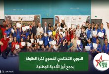 Group of students and adults posing with certificates at a sports award ceremony in a gymnasium hall.
