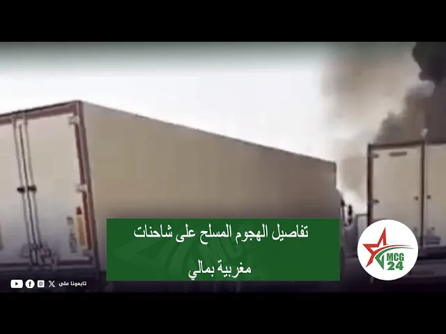 Two large trucks on a highway with dark smoke rising in the background; green Arabic caption banner about an armed attack on Moroccan trucks in Mali, with an MCG24 logo in the bottom right.