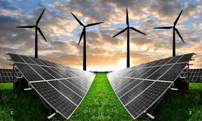 Solar panels in a green field with wind turbines against a sunset sky, representing renewable energy.