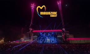 Nighttime Mawazine Rabat festival stage with blue lights, pyrotechnics, and a cheering crowd.