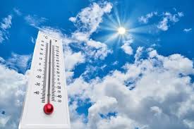 Outdoor thermometer with red mercury against a bright blue sky and sun-filled clouds