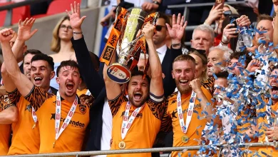 téléchargement 4 | MCG24 | موقع إلكتروني مغربي شامل متجدد على مدار الساعة Football team in orange jerseys celebrating with a large trophy raised above their heads, gold medals around their necks, confetti in blue and white.